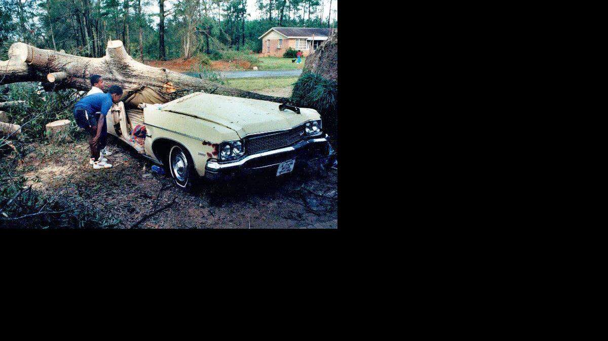 11-year-old Ricky Gilmore and 7-year-old Willie Gilmore look at a car on Sandhill Road in Eastover where Terry Capers, 30, was crushed to death by a tree.