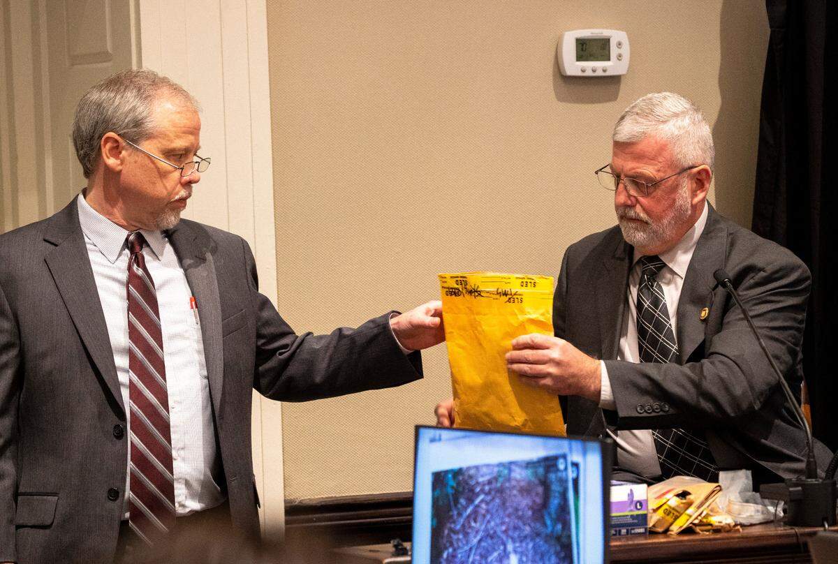 Creighton Waters, a prosecutor for the S.C. Attorney General’s office hands an evidence package to Jeff Croft, a SLED senior special agent, in the double murder trial of Alex Murdaugh at the Colleton County Courthouse in Walterboro, Monday, Jan. 30, 2023. Andrew J. Whitaker/The Post and Courier/Pool