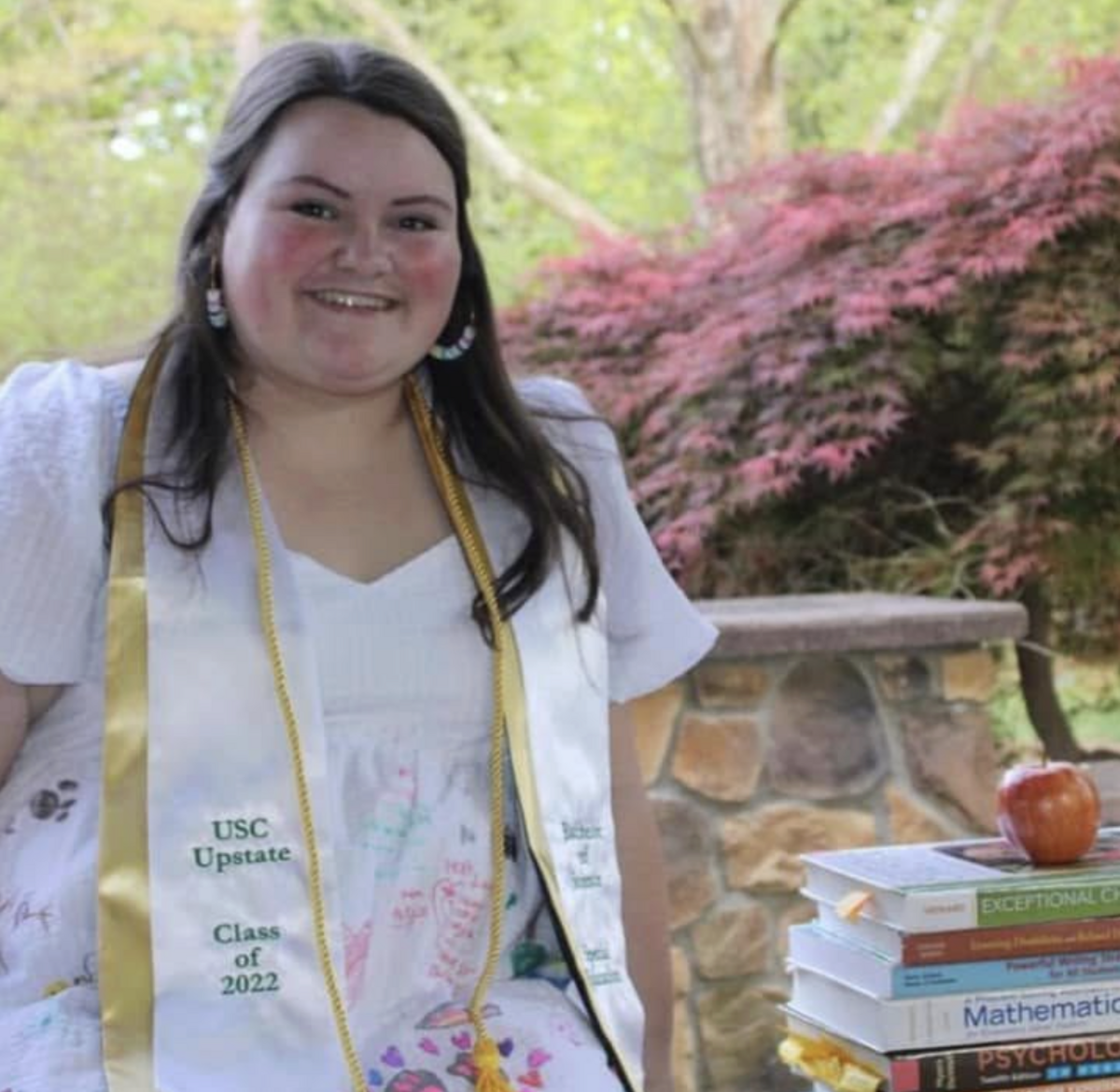 For her college graduation photos, Anna LeCoq wore a dress decorated by those she taught as a student teacher,