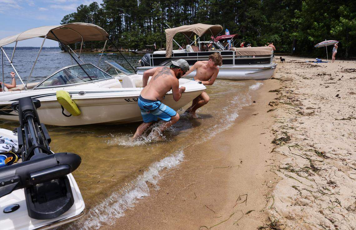 Frank Farmstead (left) and Carter Borsh pull a boat up onto the shore while spending Memorial Day at Sandy Beach on Bundrick Island on Lake Murray in Lexington on Monday, May 27, 2024.