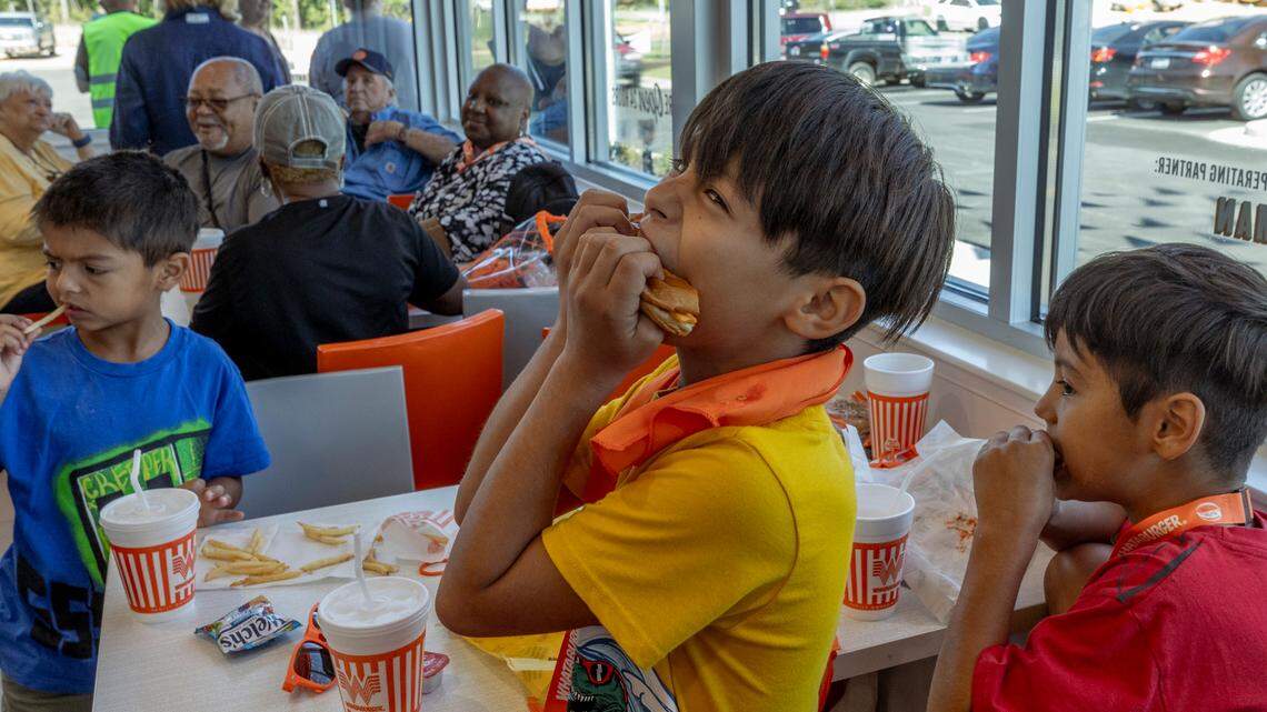 Ezra Bonilla, 9, enjoys his burger as his brothers, Alex Bonilla, 7, left, and Benjamin Bonilla, 10, eat at Whataburger during the grand opening of the Irmo location on Monday, Sept. 9, 2024.