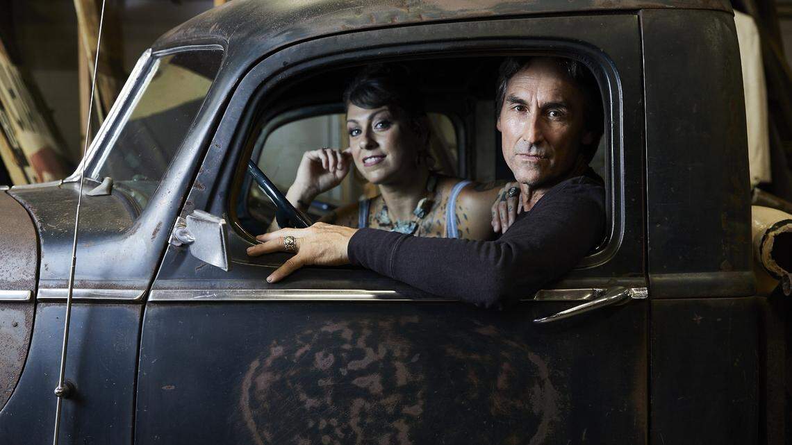 “American Pickers” cast members Mike Wolfe and Danielle Colby pose for a photo in an antique car.