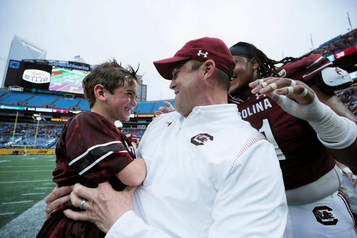 South Carolina Gamecocks head coach Shane Beamer holds his. Son Hunter after they were both doused in Gatorade shortly before his team beat North Carolina at the Duke’s Mayo Bowl at Bank of America Stadium in Charlotte, North Carolina on Thursday, December 30, 2021.