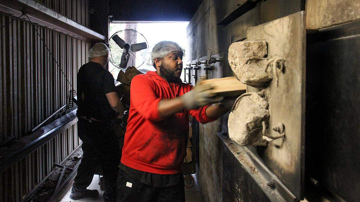 Workers load wood to keep the pits burning at Maurice’s Piggie Park BBQ. Oct. 11, 2023