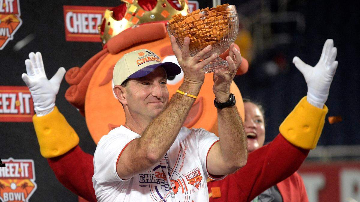 Clemson head coach Dabo Swinney holds a trophy full of crackers after winning the Cheez-It Bowl NCAA college football game against Iowa State, Wednesday, Dec. 29, 2021, in Orlando, Fla. (AP Photo/Phelan M. Ebenhack)