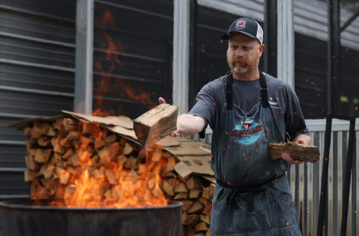 Robbie Robinson, owner of City Limits Barbeque, tosses work into a burn barrel at his West Columbia restaurant on Saturday, March 23, 2024.