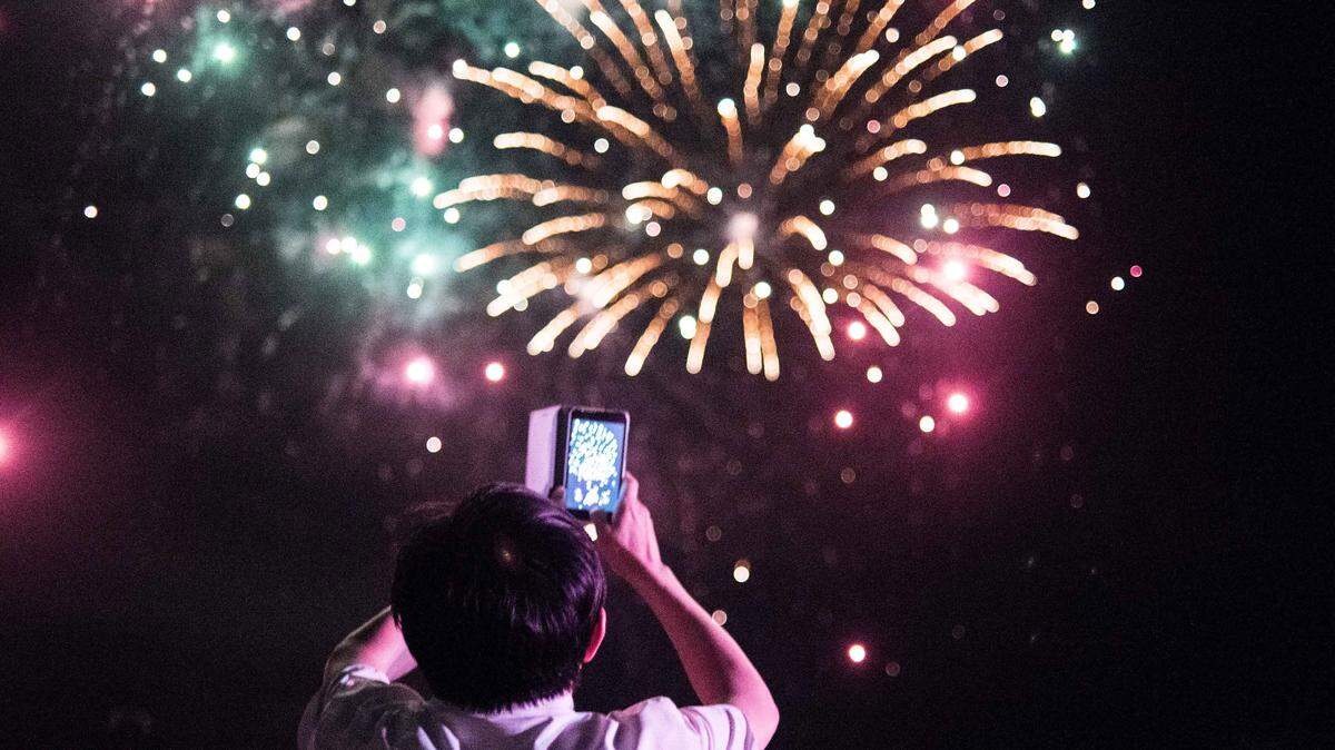 A woman records video at the 2016 Torchlight Tattoo and Fireworks display at Fort Jackson Army Base in Columbia, S.C. Fort Jackson will not host a 2019 July Fourth celebration.