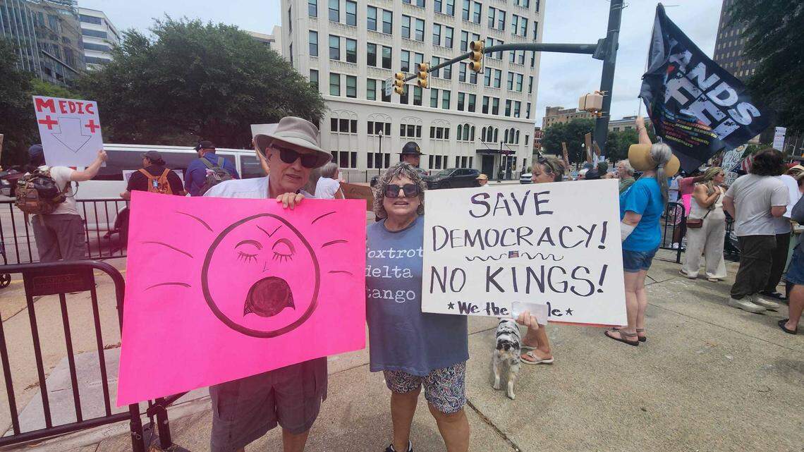 Martha Barnette stands alongside her brother, John Nelson, holding a doubled-sided sign that read, “Save our Democracy! No Kings!,” on one side and “June 14th, Barack Obama Appreciation Day! No Kings,” on the other.