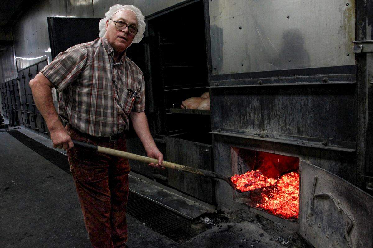 Paul Bessinger, pitmaster at Maurice’s Piggie Park BBQ, distributes coals in the restaurant’s pits. Oct. 11, 2023