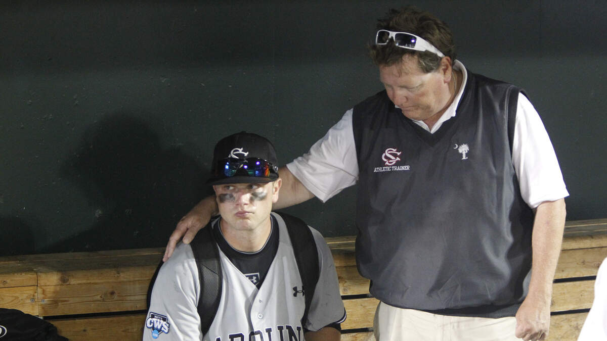 South Carolina’s Christian Walker is comforted by athletic trainer Brainard Cooper as he sits in the dugout after the Gamecocks 5-1 loss to Arizona in the first game of the final series of the 2012 College World Series at TD Ameritrade Park in Omaha, NE.