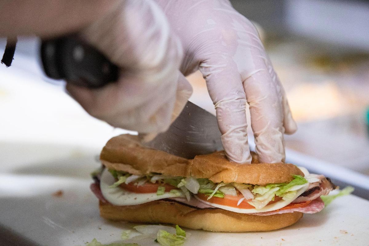 An Italian sub is sliced at Swanson’s Deli on Friday, March 25, 2022. The downtown sandwich shop is a staple of the Arcade Mall.
