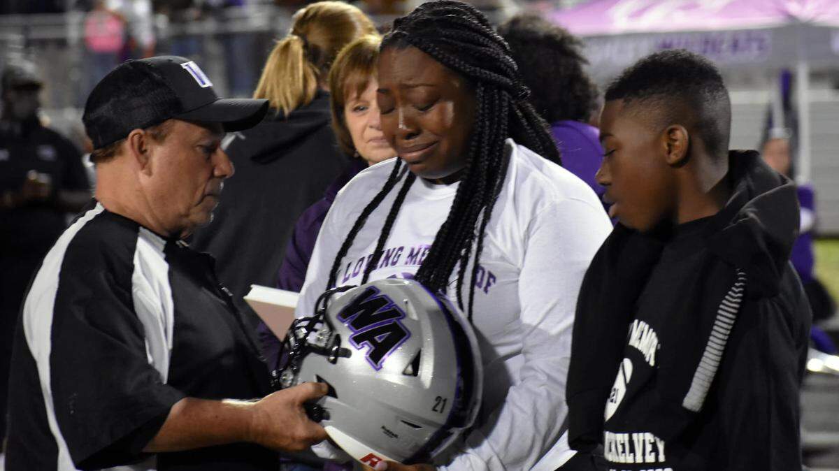 Aphrodesia McKelvey, 33, becomes emotional after she is presented with the football helmet that would have been her son’s this season. Mikell McKelvey was shot and killed on Thanksgiving morning 2020.