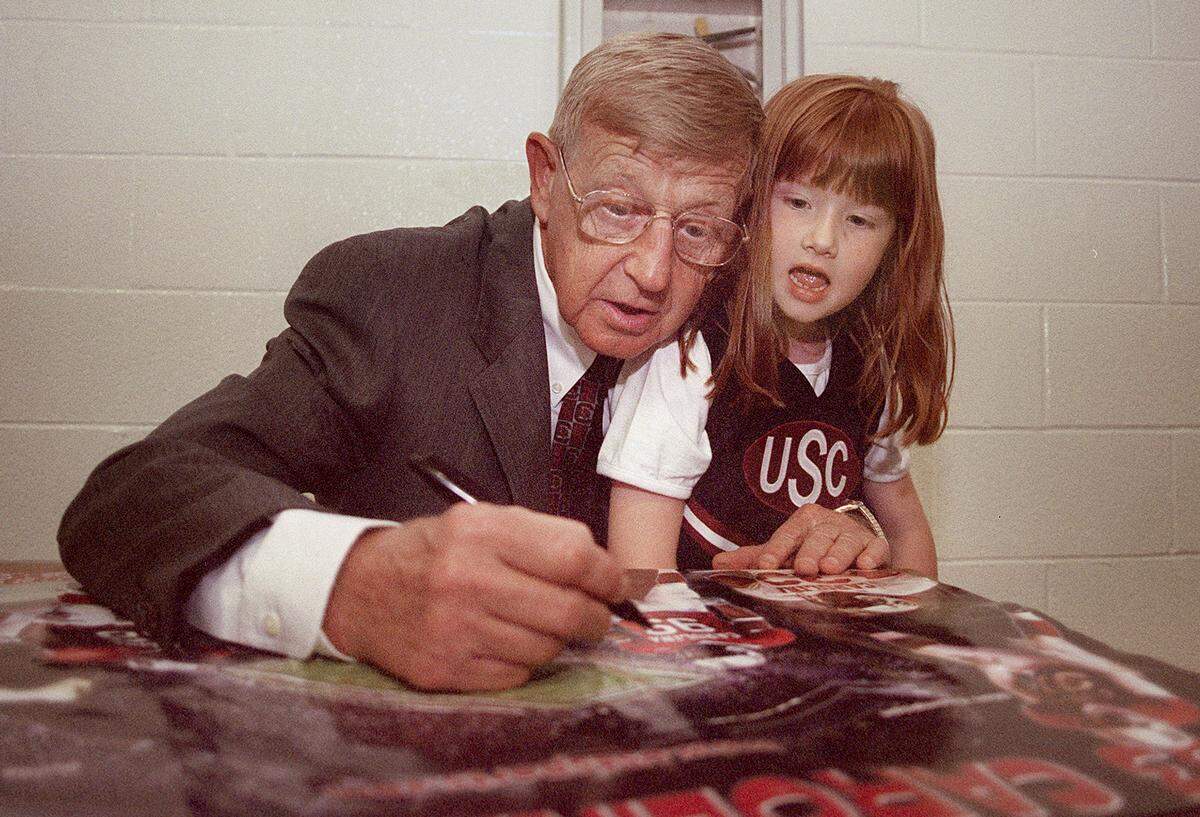 Lauren Grimm, 6, of Aiken, sits on Lou Holtz's lap as he signs a poster for her. Holtz was at the University of South Carolina-Aiken Thursday, May 22, 2003, to promote Gamecock football. 
