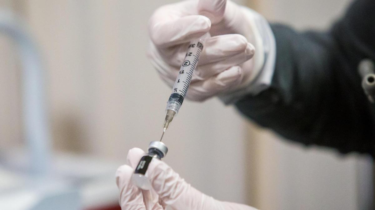 A nurse reconstitutes a vial of the Pfizer-BioNTech covid vaccine before handing it off to be administered by a fellow healthcare worker.