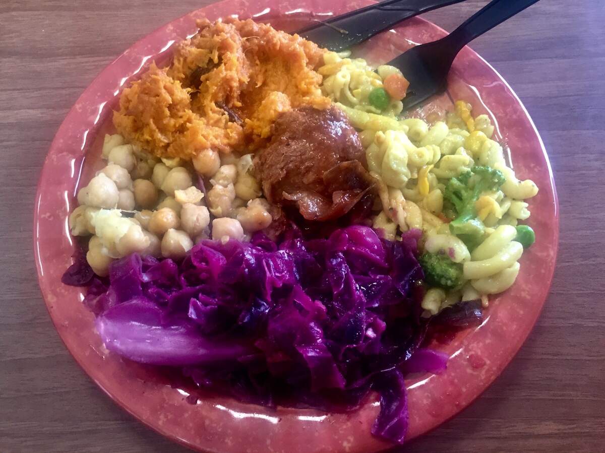 A plate of vegan soul food from Lamb’s Bread Returns The King, featuring sweet potato souffle, “goddess mac,” purple cabbage, chickpeas and a “chicken” nugget.