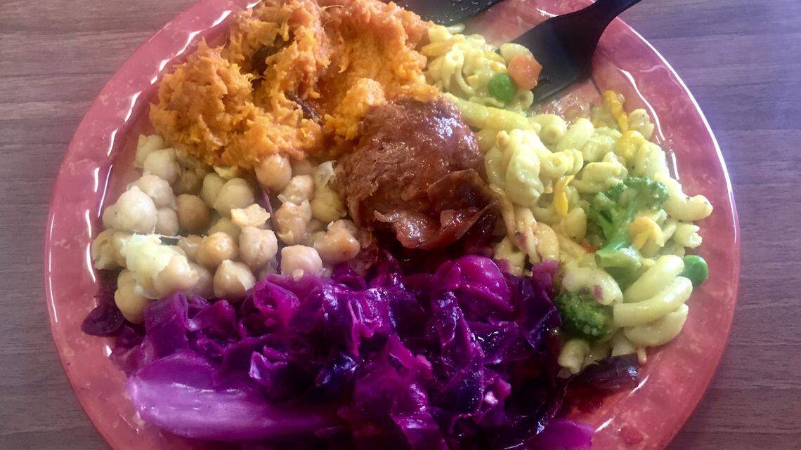 A plate of vegan soul food from Lamb’s Bread Returns The King, featuring sweet potato souffle, “goddess mac,” purple cabbage, chickpeas and a “chicken” nugget.