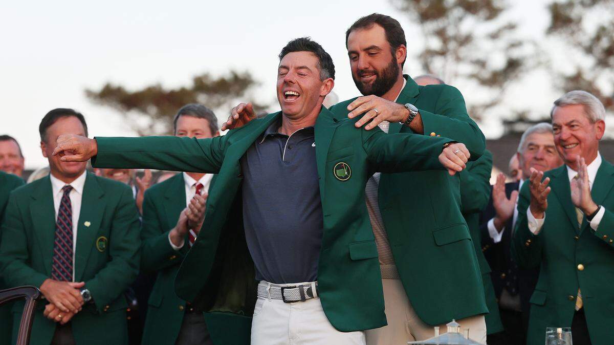 (L-R) Rory McIlroy of Northern Ireland is awarded the Green Jacket by Masters Champion Scottie Scheffler after the final round of the 2025 Masters Tournament on April 13, 2025.
