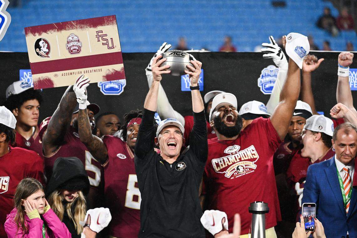 Dec 2, 2023; Charlotte, NC, USA; Florida State Seminoles head coach Mike Norvell raises the ACC Championship trophy with his players after the game against the Louisville Cardinals at Bank of America Stadium.
