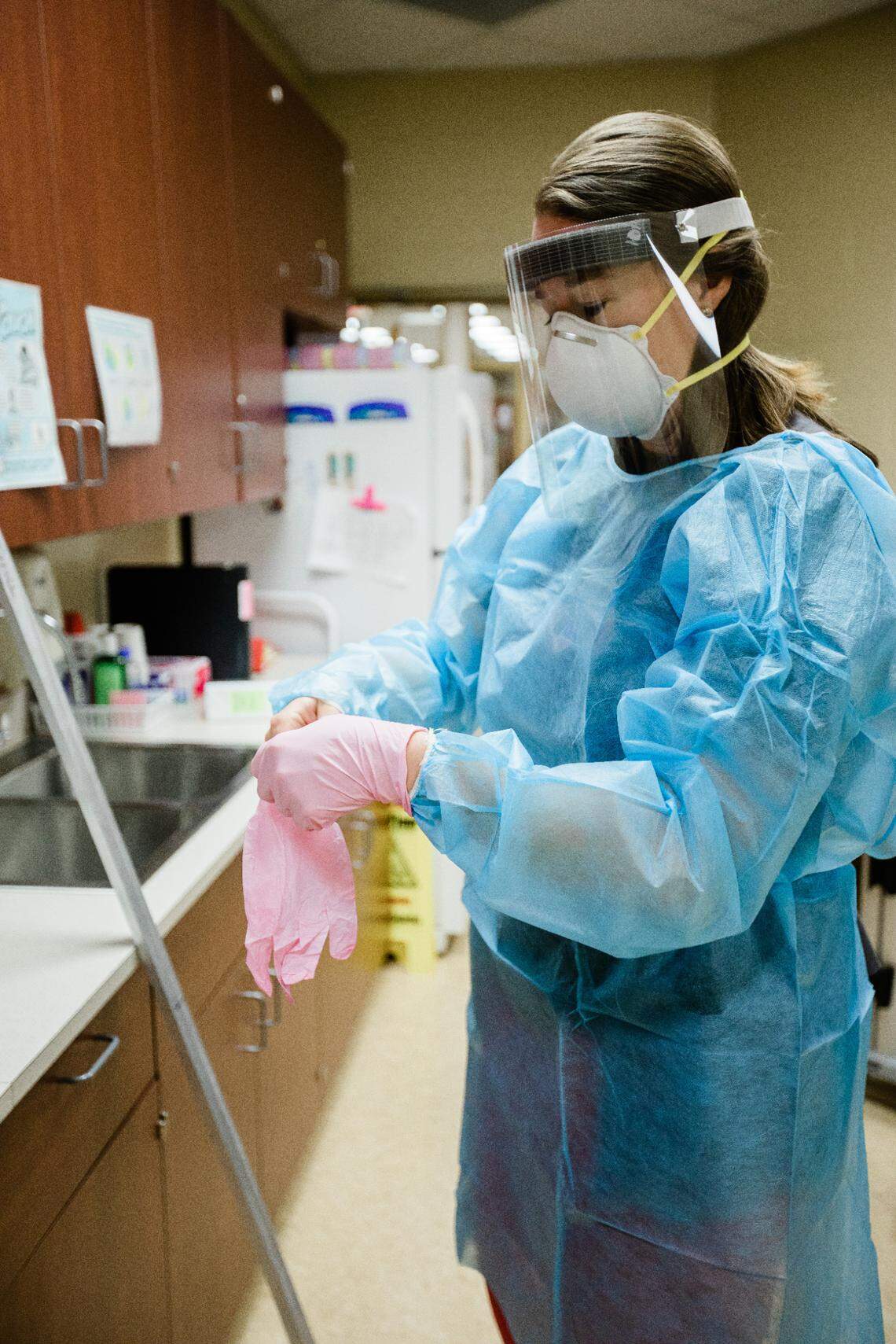 Gilbert High School nurse Elizabeth Clark demonstrates how to put on full-body protective gear.