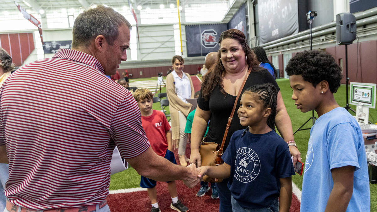 University of South Carolina head football coach Shane Beamer greets Carina Hart, 7, her brother Dominic Hart, 10, and their mother Kate Hart after awarding Joseph Keels Elementary School and three other Richland District District Two schools with donations through the Beamer Family Foundation.