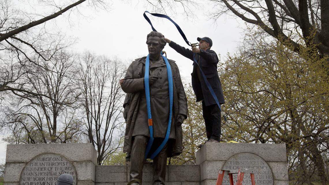 A worker tosses a strap over the 19th century statue of Dr. J. Marion Sims, Tuesday, April 17, 2018, in New York's Central Park.  Sims was known as the father of modern gynecology, but critics say his use of enslaved African-American women as experimental subjects was unethical. The statue is being moved to Green-Wood Cemetery in Brooklyn, where Sims is buried.