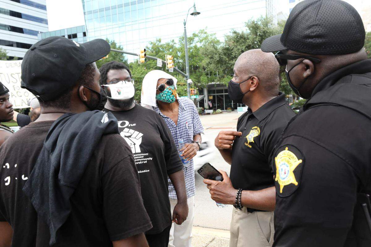 Capt. Wendall Harris, second from right, and Deputy Lawrence Brewer, with the Richland County Sheriff’s Department, speak with Jerome Bowers, second from left, and other protesters during a rally at the South Carolina Statehouse. Protesters marched and rallied to encourage people to register to vote. 8/28/20