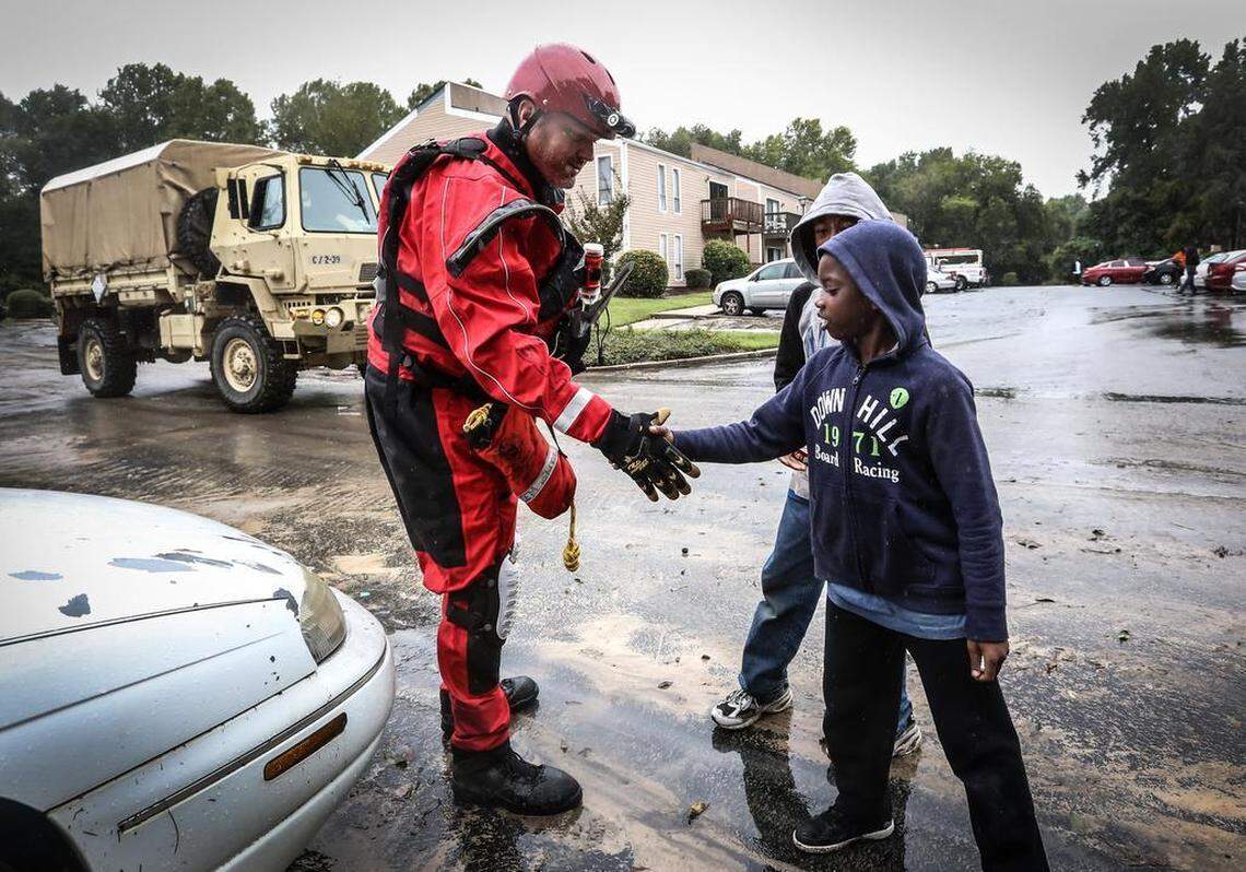 Zahid and Davon Richardson are greeted by a rescue team in the Shandon Crossing apartment complex. Rescue crews from across the country worked to help those in need after rain and flood water ravaged the Columbia, S.C. area.