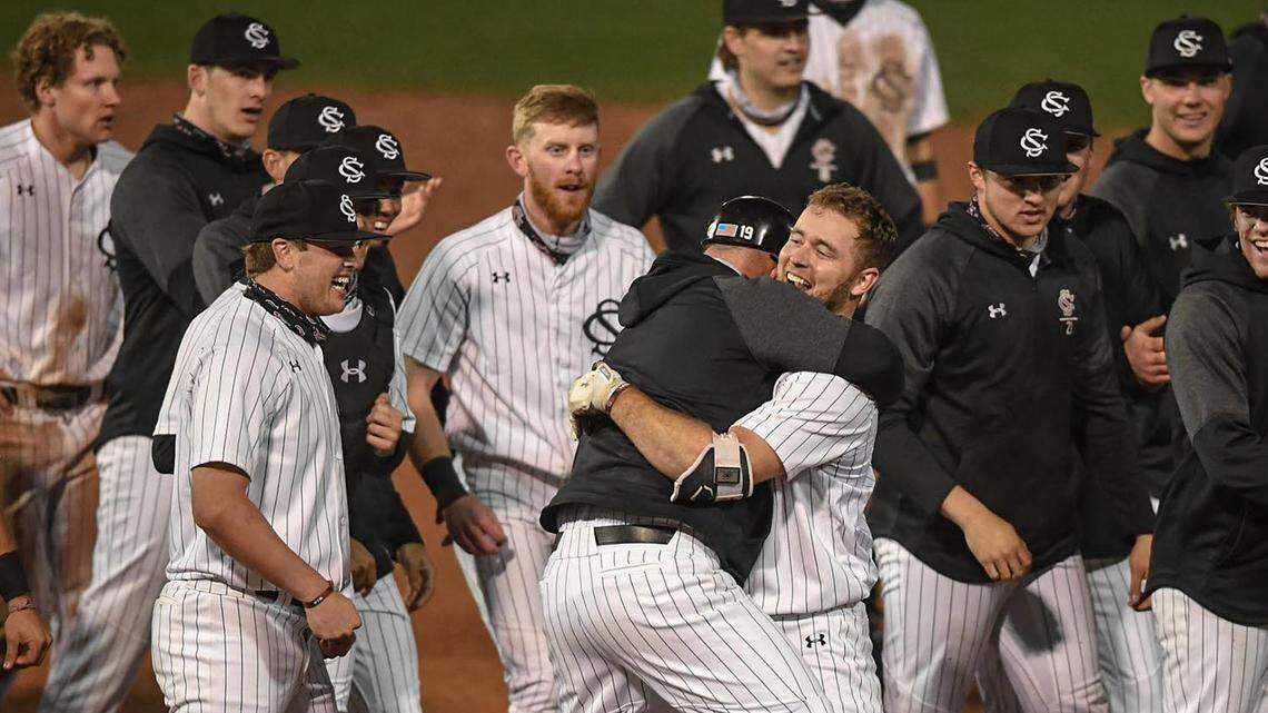 South Carolina teammates surround senior Andrew Eyster(11), who drove in teammate Brady Allen(33) with a game-winning double during the bottom of the eleventh inning during the Reedy River Rivalry at Fluor Field in Greenville, S.C. Saturday, February 27,2021.