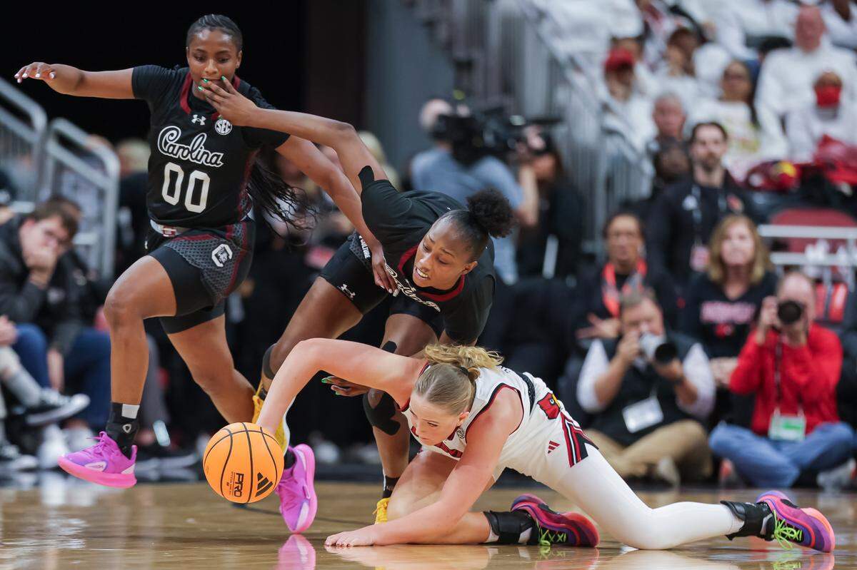 Ta'Niya Latson #00 and Joyce Edwards #8 of the South Carolina Gamecocks chase down a loose ball against Laura Ziegler #0 of the Louisville Cardinals during the second half at KFC YUM! Center on December 4, 2025 in Louisville, Kentucky.