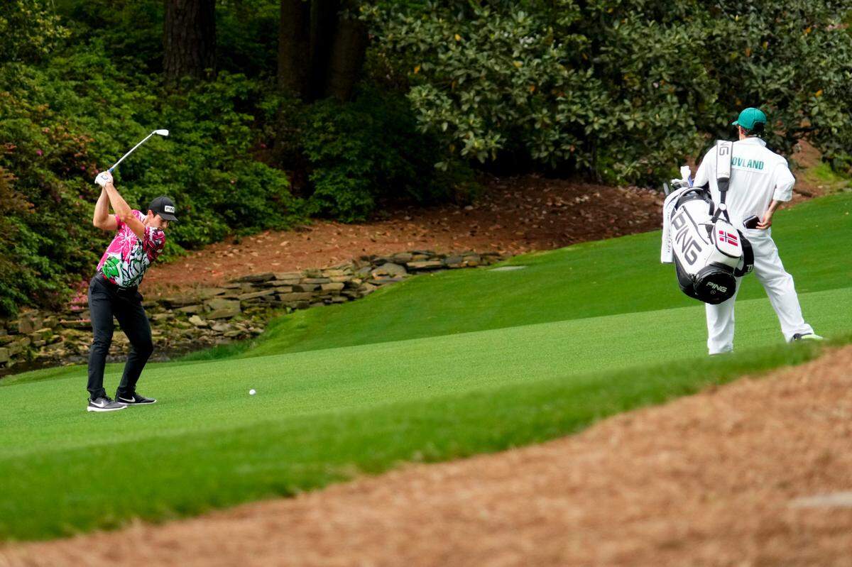 Viktor Hovland hits from the 13th fairway as caddie Shay Knight watches during the first round of The Masters golf tournament.