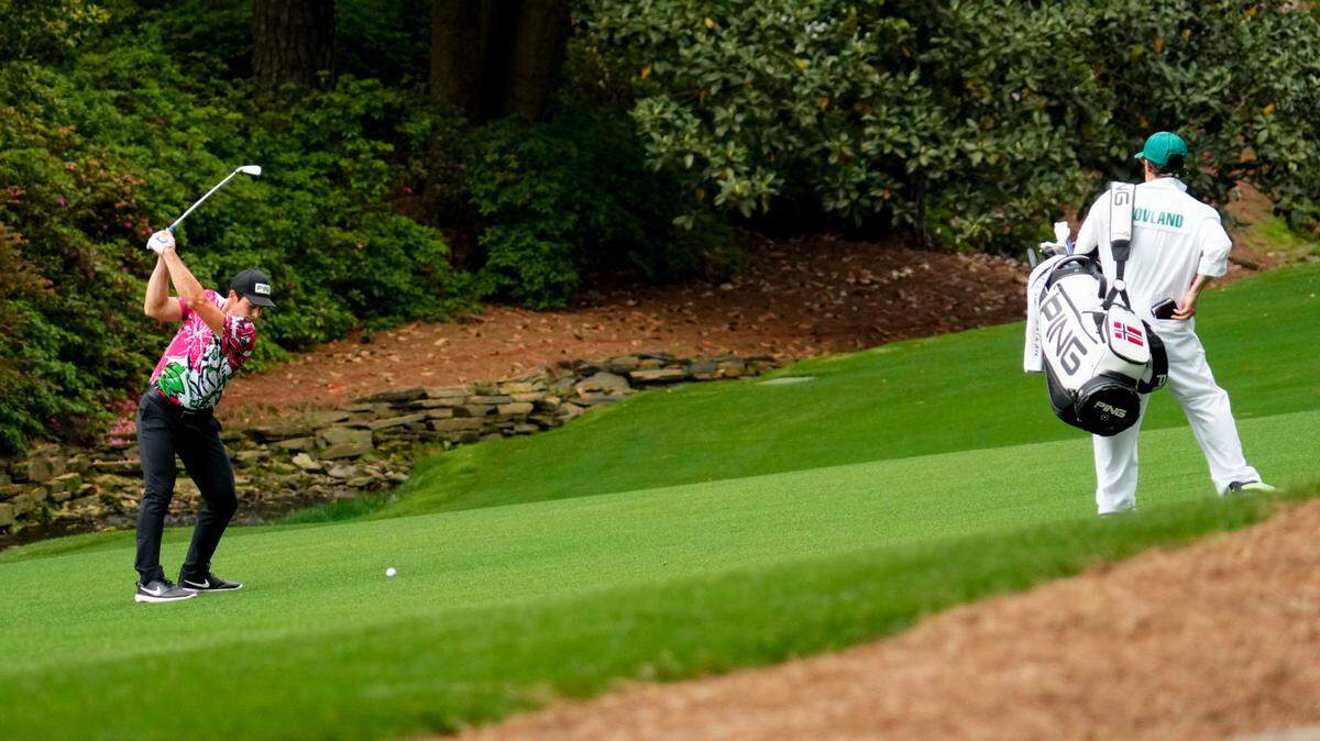 Viktor Hovland hits from the 13th fairway as caddie Shay Knight watches during the first round of The Masters golf tournament.