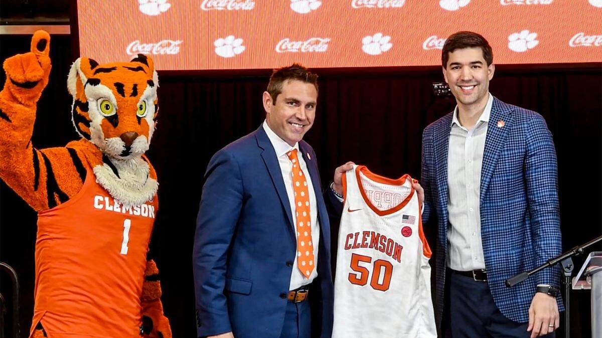 Graham Neff, right, Athletic Director, poses Tuesday with Shawn Poppie, Clemson University Tigers women’s basketball coach with a jersey at a press conference introducing Poppie at Littlejohn Coliseum.