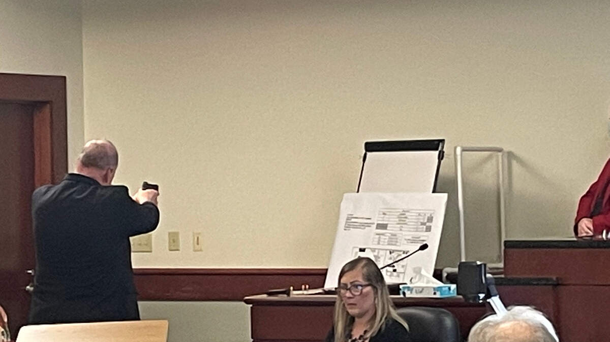 Charles Mills, a gun expert with FN manufacturer, aims an unloaded gun before pulling the trigger in the case of Adam Lazzarini, a doctor accused of shooting a man.