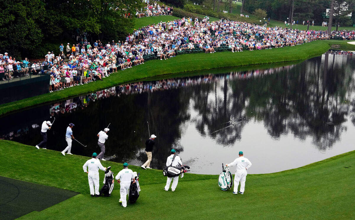 Tom Hoge, Ben Carr, Russell Henley and Larry Mize skip balls across the pond on no. 16 during a practice round for The Masters golf tournament at Augusta National Golf Club.