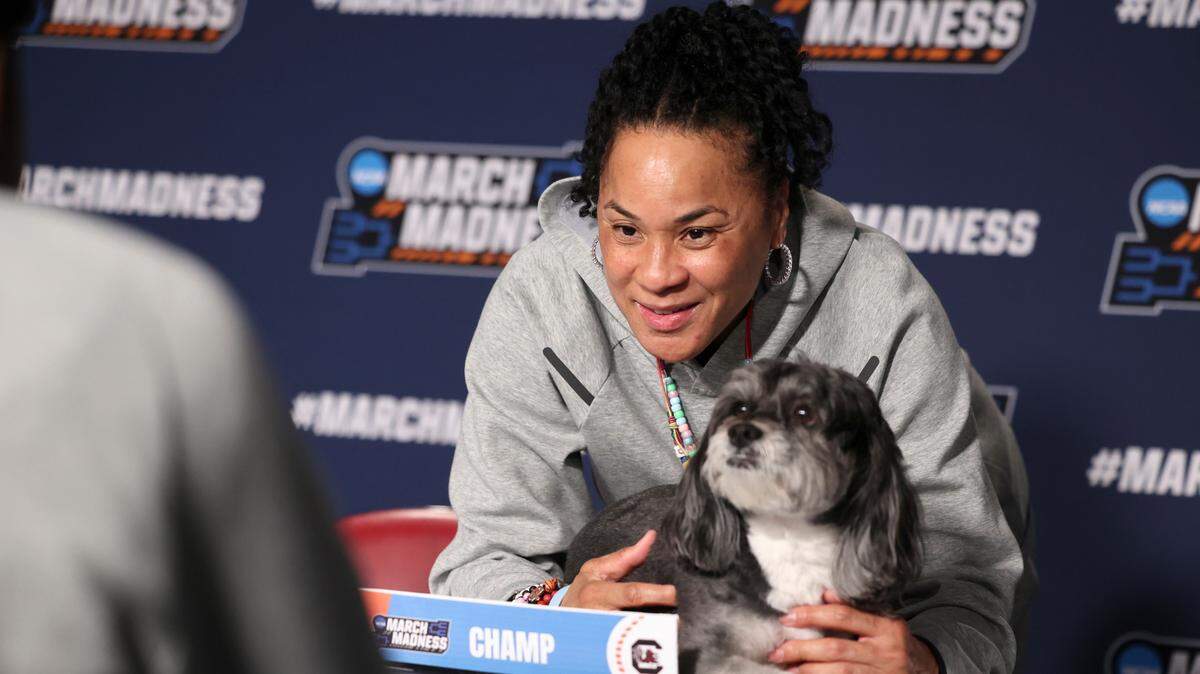 University of South Carolina Head Coach Dawn Staley poses for a photo with Champ behind the nameplate that Tennessee Tech’s head coach Kim Rosamond gave her after a press conference at the Colonial Life Arena on Thursday, March 20, 2025. The Gamecocks face Tennessee Tech in the first round game of the NCAA Tournament.