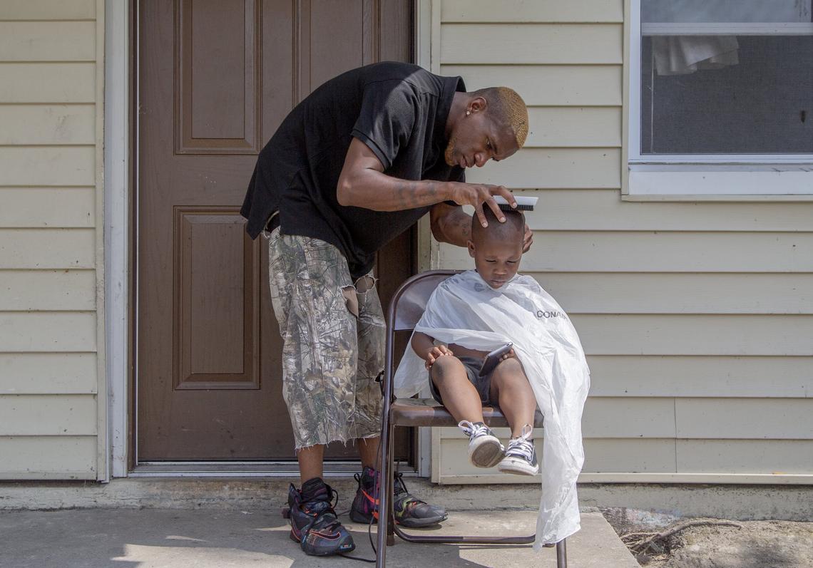 Marcus Bess gives his step son, Shawnteze’ Bouknight, 4, a haircut on the front porch of his his home in The Colony Apartments, a neighborhood that ends where North Pointe Estates begins in Columbia, SC. Bess hopes to change the reputation of the neighborhood by running free haircut events in the neighborhood.