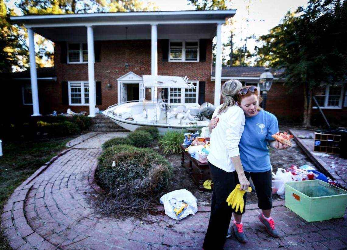 Beverly Steinhaus hugs Carol hill, a friend who helped clean her house on Burwell Street after it was submerged in flood water.