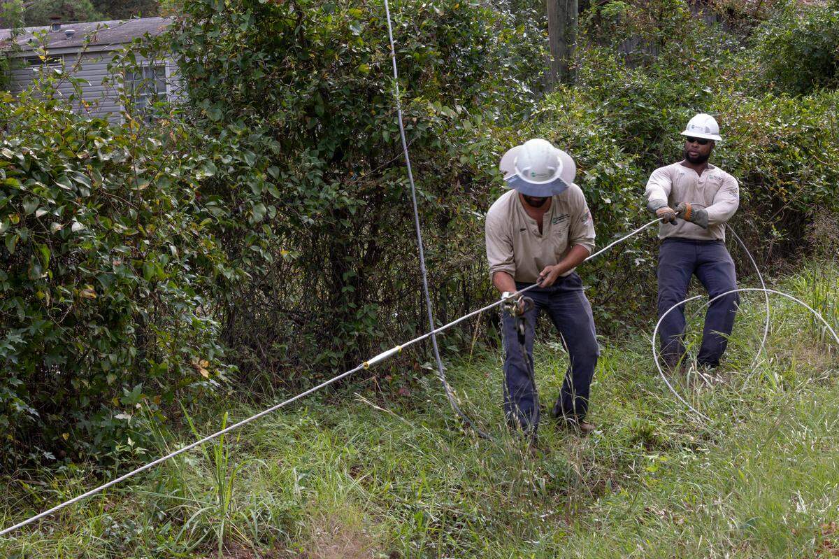 Aiken Electric Cooperative lineman Dilan Havird, left, and Ellis Crawford prepare an electrical line to be hoisted to a utility pole while repairing downed power lines in Edgefield on Tuesday, Oct. 1, 2024. High winds from Hurricane Helene toppled trees leaving thousands without power. The damage to rural areas is so bad that along many roads, the entire electrical infrastructure needs to be rebuilt.