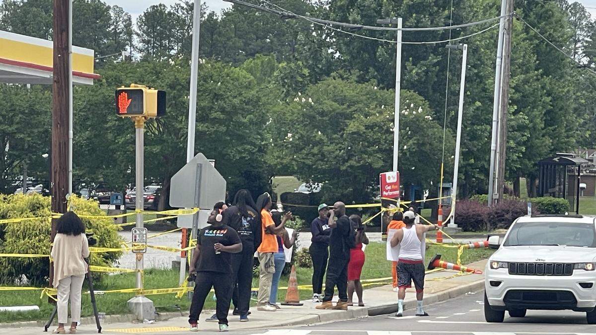 Protestors line the sidewalk Tuesday afternoon outside the Shell station formerly owned by Chikei Rick Chow, outraged by his acquittal late Monday night.