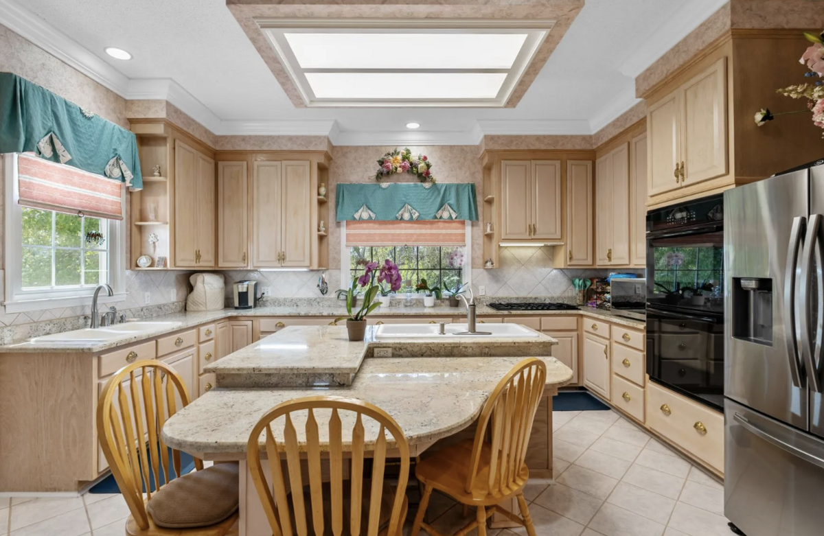 The kitchen has gas cooking, double ovens, granite countertops, stainless appliances and large windows.