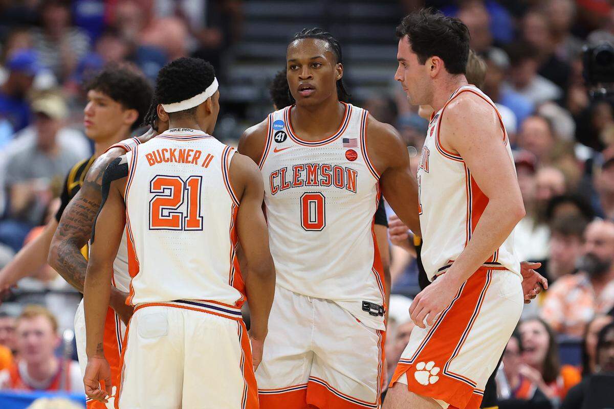 RJ Godfrey (0) of the Clemson Tigers huddles with Ace Buckner (21) and Nick Davidson (11) during the second half against the Iowa Hawkeyes in the first round of the 2026 NCAA Men's Basketball Tournament at Benchmark International Arena on March 20, 2026 in Tampa, Florida.