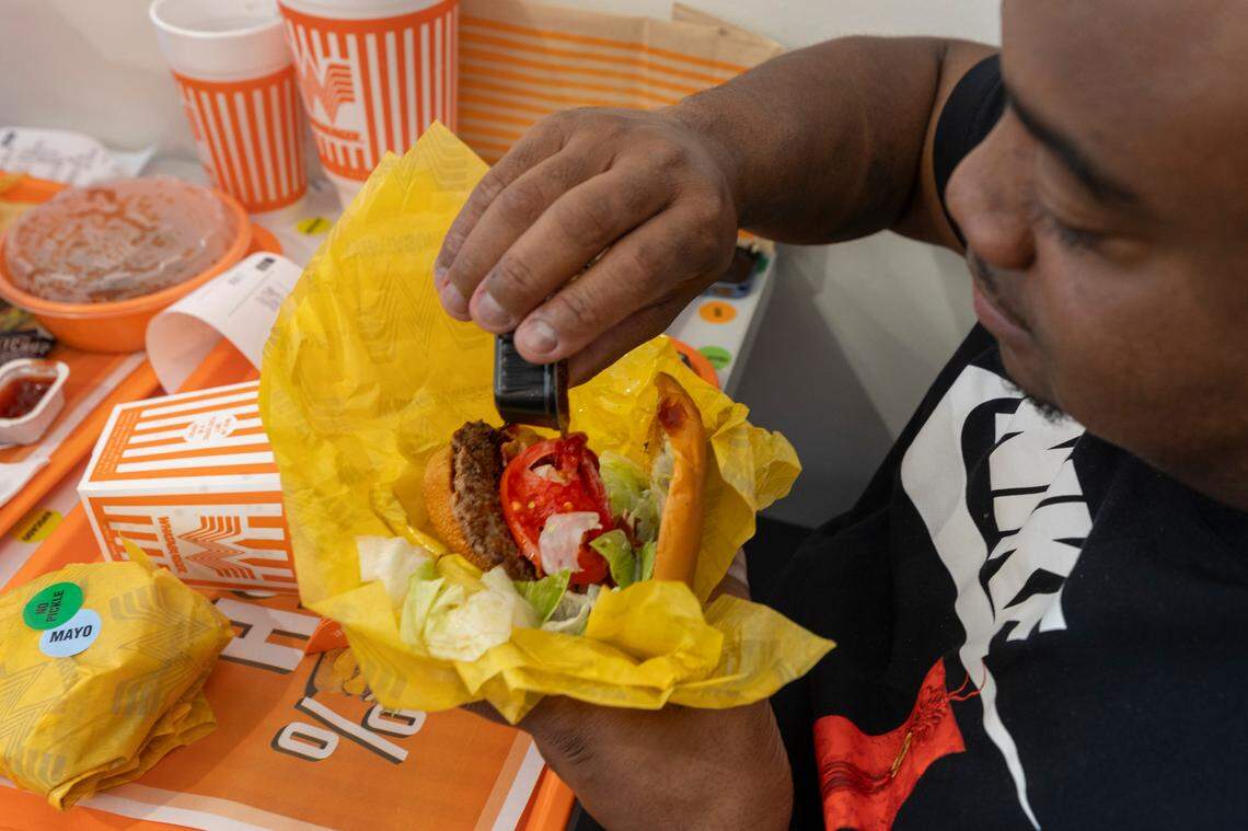 Eric Parker puts spicy ketchup on his burger while dining during the grand opening of the Whataburger in Irmo on Monday, Sept. 9, 2024.