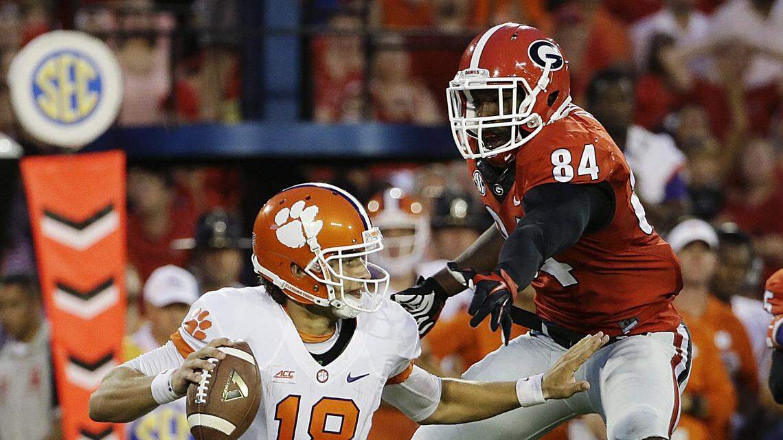 Clemson quarterback Cole Stoudt, left, scrambles to get away from the defense of Georgia’s Leonard Floyd in the second half of an NCAA college football game, Saturday, Aug. 30, 2014, in Athens, Ga. Georgia won 45-21. (AP Photo/David Goldman)
