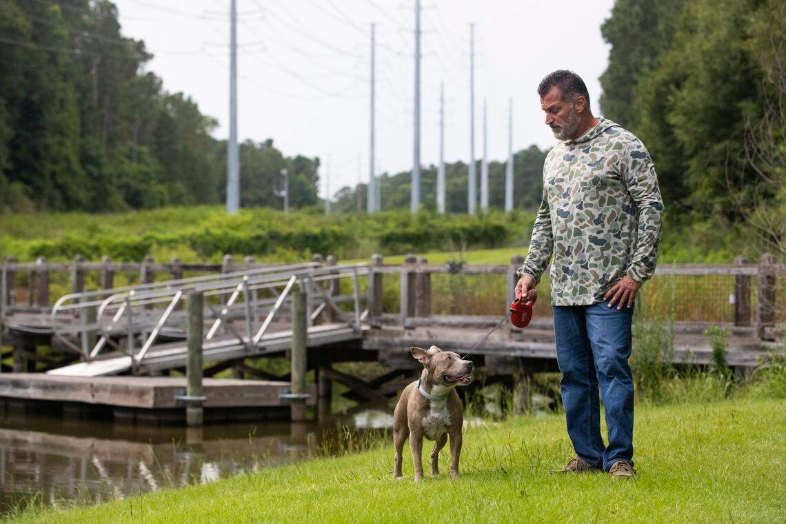 Craig Baxley walks his neighbor’s dog, Shadow, at Saluda Shoals Park on Tuesday, July 13, 2021.