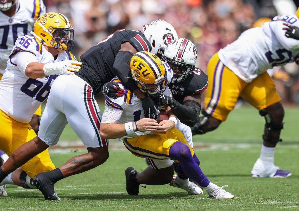 From Sept. 14, 2024: LSU quarterback Garrett Nussmeier (13) gets wrapped up by South Carolina edge Kyle Kennard (5) and linebacker Bam Martin-Scott (22) 