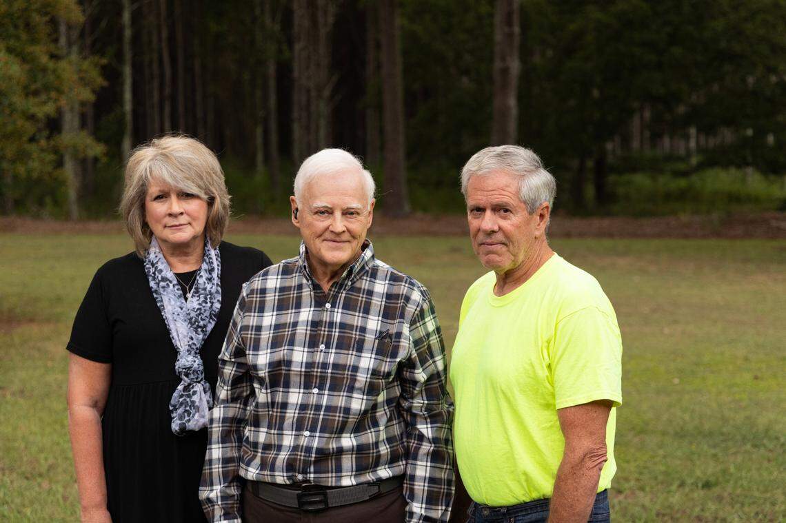 Charles Blackmon stands between Chris Heald and her husband, Richard Heald at his home in Laurens County, South Carolina on Wednesday, September 18, 2024. After the Healds moved to the Mountville community, they began to smell odors from large poultry farms near their home.