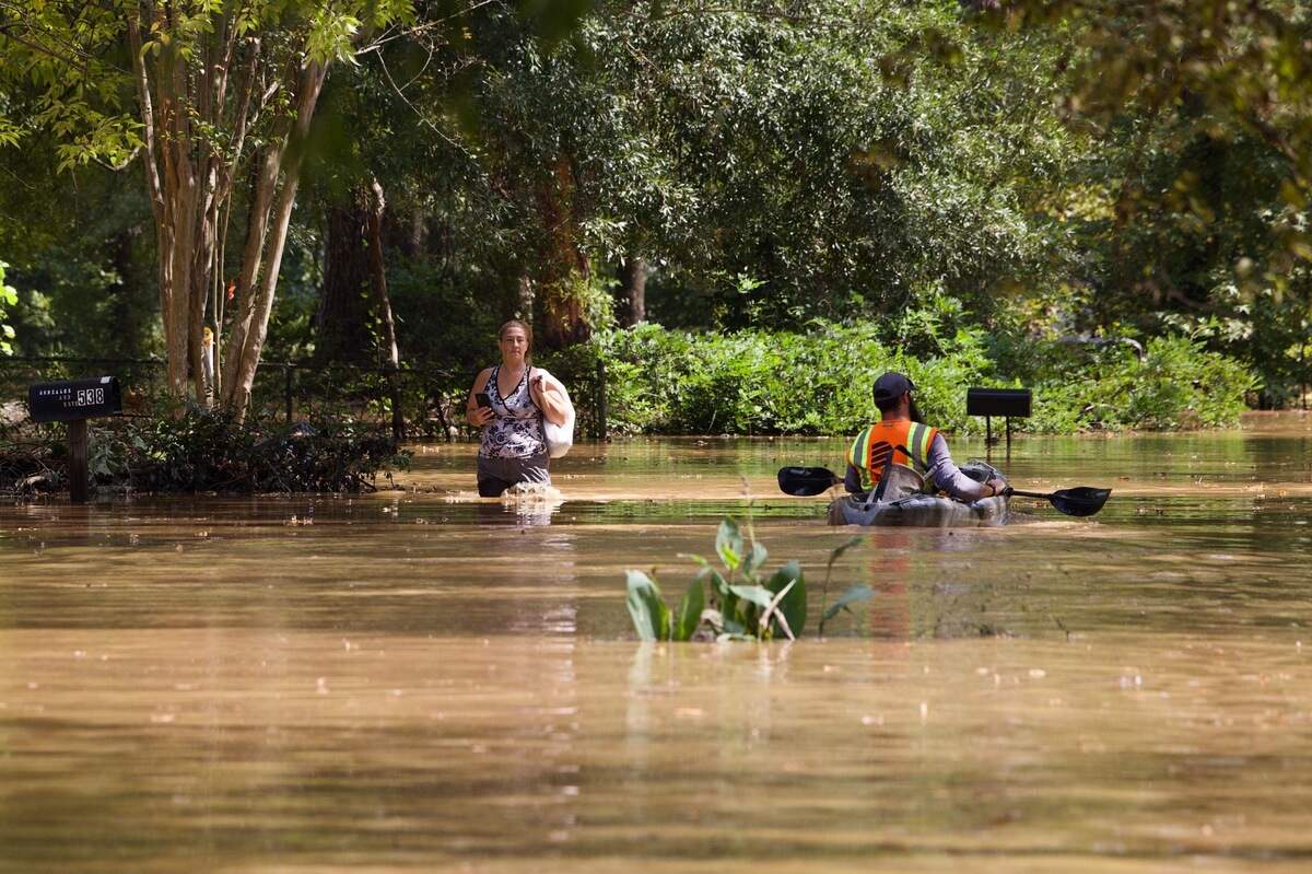 Krystal Nye takes a plastic bag of clothes from a family member’s home to deliver to her after her home was flooded in the aftermath of Hurricane Helene. Hudson Venue and the surrounding area in Cayce, South Carolina, is flooded.
