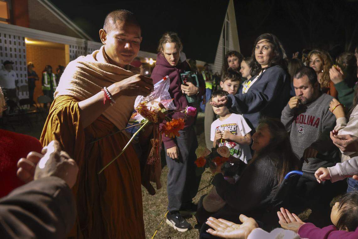 A Buddhist monk offers blessing bracelets to a crowd gathered at Nazareth Methodist Church on Thursday, Jan. 8, 2026. The monks rested for the night at the church while taking a break from their 2,300-mile Walk for Peace.