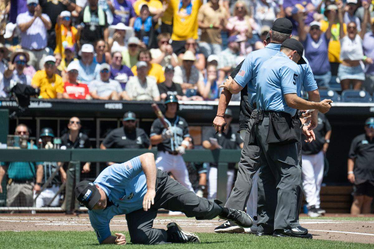 An umpire trips during the game between the Coastal Carolina Chanticleers and the LSU Tigers during the first inning at Charles Schwab Field. 