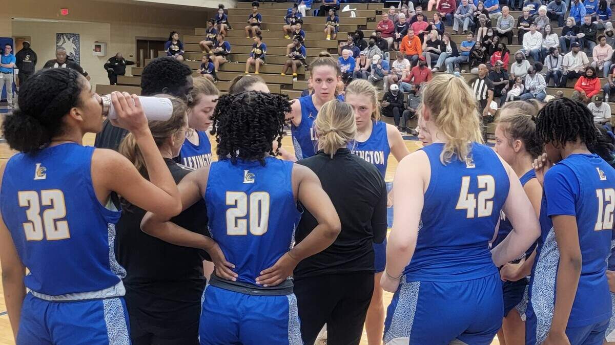 Lexington players huddle up and listen to coach Molly Goodrich during a timeout in Tuesday’s Class 5A playoff game against Sumter.